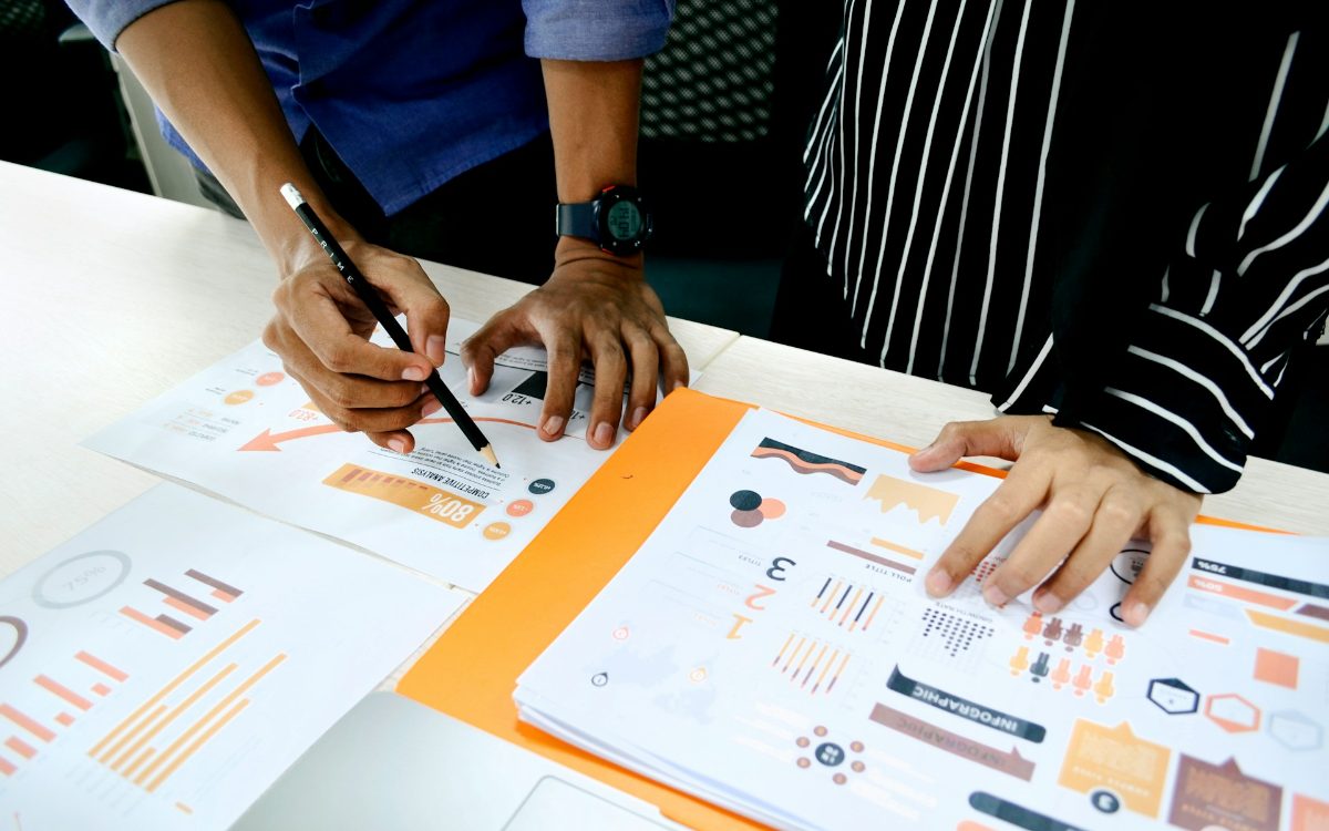 Two people reviewing printed charts and analysis on a desk